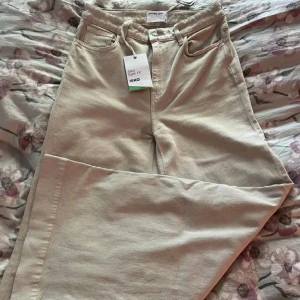 Beige jeansbyxor från Designers Remix - Snygga beige jeansbyxor från Designers Remix med hög midja och vida ben. Perfekta för en avslappnad stil. Tillverkade i ett hållbart material från ISKO Earth Fit. 