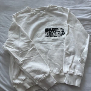 Vit sweatshirt med tryck från Zara - Vit sweatshirt från Zara med svart grafiskt tryck både fram och bak. Tröjan har rund hals, långa ärmar och ribbade muddar vid ärmslut och nederkant. Skön och avslappnad passform, perfekt till jeans eller joggers.