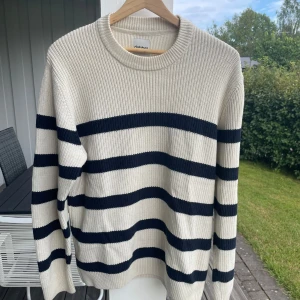 Randig stickad tröja från Dobber - Jättesnygg stickad tröja från Dobber i offwhite med breda mörkblå ränder. Tröjan har rund halsringning, ribbade muddar och lång ärm. Inga fläckar eller skador. Passar normalt, säljer pga för liten storlek för mig.