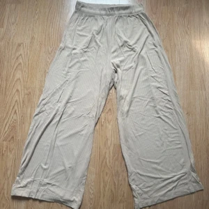 Beige pull-on byxa - Säljer ett par beige pull-on byxa byxor med plisserad struktur och resår i midjan. Byxorna är croppade och har en avslappnad, loose passform. Perfekta för varma dagar och riktigt sköna att bära. Materialet känns lätt och luftigt