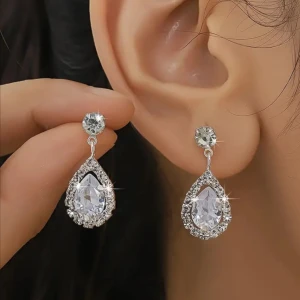 Glittriga örhängen liknande lily and rose  - Superfina örhängen i silverfärg med stora, droppformade kristaller omgivna av mindre gnistrande stenar. Perfekta för dig som vill sticka ut och addera extra bling till din look. Snyggt och trendigt statement-smycke!