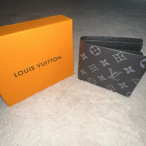 Svart axelväska med orange box - Säljer en stilren svart axelväska med struktur och detaljer i grått. Kommer med en ikonisk orange box. Perfekt storlek för det viktigaste och enkel att matcha till olika outfits.