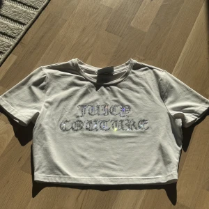 Vit croppad Juicy Couture topp - Snygg vit Juicy Couture crop t-shirt i mjukt tyg, dekorerad med glittrande strasstenar som stavar “JUICY COUTURE” i gotisk stil. Perfekt skick – endast provad. Stretchigt material, sitter figurnära men bekvämt. Ikonisk Y2K-känsla, passar perfekt till jeans, cargo eller kjol.  Några få stenar saknar men detta är inget som läggs märke till🫶🏻 
