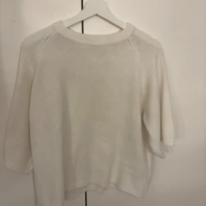 Vit stickad tröja med trekvartsärm - Mysig vit stickad tröja med rund halsringning och trekvartsärmar. Tröjan har en enkel och clean design som är lätt att matcha med olika outfits. Perfekt för lager-på-lager och chill dagar.