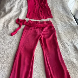 En rosa komplett - Säljer en komplett med byxor, tröja och ett bälte som går att ta bort om man inte tycker om den. Detta passar för storlek S och eventuellt M. Men det är i bra skick och mycket skönt material 