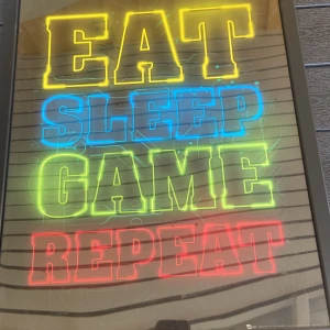 Eat Sleep Game Repeat - Cool affisch med neonfärgade bokstäver: 'Eat Sleep Game Repeat'. Tavlan är I bra skick, 50kr
