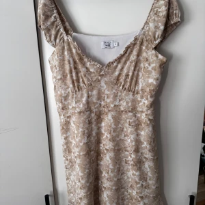 Beige kortklänning  - Supersöt kortklänning i beige och vitt från NA-KD. Fin passform