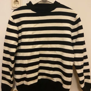 Randig svartvit stickad tröja - Snygg stickad tröja med breda svarta och vita ränder. Tröjan har rund halsringning och långa ärmar. Perfekt för dig som gillar klassisk stil med en modern twist. Mjuk och skön att bära, passar till jeans eller kjol.