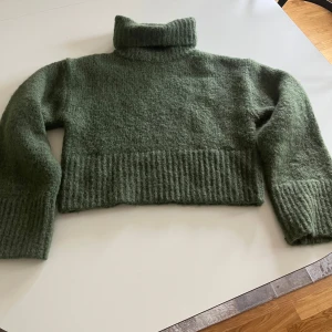 Grön stickad polotröja från Zara - Mysig mörkgrön stickad polotröja från Zara med croppad passform. Tröjan har bred ribbstickad kant nedtill och vid ärmslut, samt en hög, vikt polokrage. Nypris: 349kr, använt 1 gång🩷