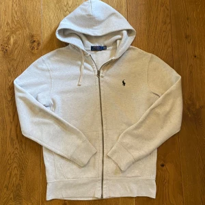 Grå Ralph Lauren ziphoodie - Mycket fint skick utan defekter, 10/10 Passar bra om du är runt 170-180, passar perfekt på mig som är 180 cm (se bild) Kom gärna med frågor eller prisförslag!