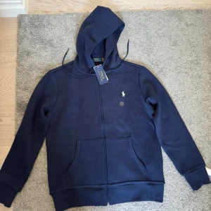 Ralph Lauren zip hoodie - Säljer en helt ny Ralph lauren zip hoodie. Med tags kvar. Bra passform perfekt för sommarkvällar eller nu till hösten. 600kr, kan gå ner lite i pris vid snabb affär.