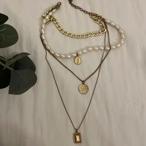 Layered halsband med pärlor och guld - Snyggt lager-på-lager halsband med tre kedjor: en chunky guldfärgad kedja, en rad vita pärlor med medaljong och två tunna guldfärgade kedjor med runda och rektangulära hängen. Perfekt statement-piece med mix av pärlor och metall. Tyvärr har dem 2 tunna banden och ”kläman” blivit lite rostiga men super bra för en DIY projekt eller kanske bara klippa bort dessa 2 tunna banden? 🌸