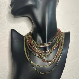 Fyra chunky vintagehalsband - retro metall i lager-på-lager-look - Boxkedja - 70-tal 80-tal - Auktionsfynd  - Set med fyra äkta vintagehalsband i boxkedjor: antikguld, koppar, mässing och en matt khaki-bronsig ton. Alla är separata men designade för att bäras ihop i en kraftfull lager-på-lager-look. Längd ca 75–100 cm. Auktionsfynd från 70-/80-talet med retrokänsla, tyngd och tydlig attityd. Prutning accepteras inte, men jag erbjuder rabatt vid köp av flera saker. Jag rensar garderoben – kika gärna på mina andra annonser också!  ⸻