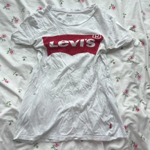 Vit Levi's t-shirt med röd logga - Vit t-shirt från Levi's i bomull med klassisk röd logga framtill. Modellen är kortärmad och har en normal passform. 