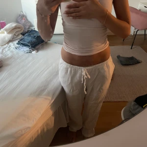 Vita linnebyxor med snörning - Säljer ett par vita linnebyxor med avslappnad passform och snörning i midjan. Byxorna är raka i modellen och perfekta för en chill och luftig stil. Superbekväma och lätta att matcha med allt.