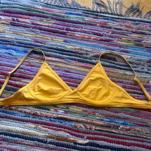Gul bikiniöverdel från NA-KD - Snygg gul bikiniöverdel från NA-KD med triangelformade kupor och tunna, justerbara axelband. Enkel och stilren design som ger en fräsch sommarkänsla. Perfekt för stranden eller poolen!