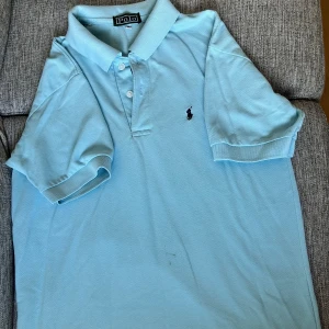 Ralph Lauren piké  - Klassisk vit piké från Ralph Lauren – stilren, tidlös och alltid rätt. Tillverkad i mjuk bomull med den ikoniska broderade ponnyn på bröstet. Perfekt för både vardag, jobb eller mer uppklädda tillfällen. En mångsidig favorit i garderoben som aldrig går ur stil.