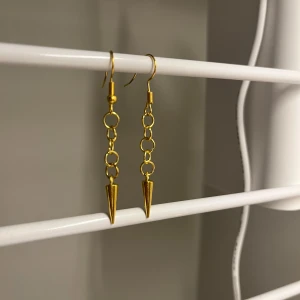 Guldiga kedjeörhängen med spikes - Snygga örhängen i guld med kedjor och spetsiga spikes längst ner. De har en cool och edgy vibe, perfekta för att lyfta din stil. Hängande modell som ger ett statement till din look. Handgjort 