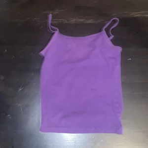 Lila linnetopp från H&M - Säljer en enkel och snygg lila linnetopp från H&M med smala axelband. Toppen är gjord i mjuk bomull med lite stretch, perfekt för varma dagar eller som lager under andra plagg. Stilren och lätt att matcha med jeans eller shorts.