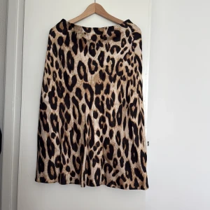 Leopardmönstrad satinkjol från HM - Vadlång, lätt klockformad, kjol från HM med leopardmönster i beige och svart. Resår i midjan. 