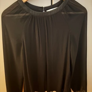 Svart blus från Boden - Säljer en svart blus från Boden i storlek UK 8. Blusen har långärmade, lätt transparenta ärmar. Köpt second hand men i väldigt bra skick. Perfekt nu till hösten!
