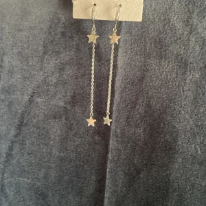Silvriga örhängen med stjärnor!⭐️  - Långa silvriga örhängen med tunna kedjor och små stjärnhängen både upptill och nedtill. Örhängena har en cool och trendig vibe, perfekta för att ge din look lite extra edge. Stjärnorna är enkla men ändå iögonfallande och passar dig som gillar detaljer!💞