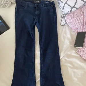 Mörkblå bootcut lowwaisted jeans från Replay - Snygga mörkblå jeans från Replay i klassisk bootcut-modell. Jeansen har fem fickor, normal passform och är tillverkade i stretchigt denim för extra komfort. Perfekta för dig som gillar en tidlös look med lite utsvängda ben.
