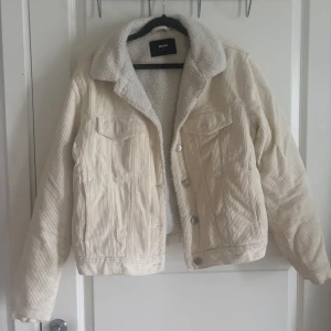 Beige teddyjacka i manchester från BikBok - Supermysig beige teddyjacka från BikBok i manchester med vit teddyfoder på insidan. Klassisk jeansjacke-modell med knappar framtill och två bröstfickor. Perfekt för höst och vinter när du vill vara både varm och snygg.