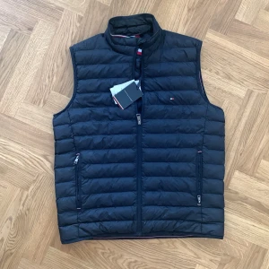 Mörkblå väst Tommy Hilfiger GRATIS FRAKT - Köpte den för 2099 sek, för ett halvår sedan. quiltad design och dragkedja framtill. Västen har två fickor med dragkedja och diskret      Storlek LARGE 