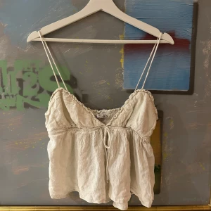 Beige topp från Zara - Supersöt beige topp från Zara med tunna axelband och rynkade detaljer längs kanterna.