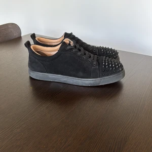 Christian Louboutin svarta sneakers med nitar - Svarta sneakers i mocka från Christian Louboutin. Bra kvalité. Storlek 44 men passar 43. Skorna saknar en nit, däremot inget man tänker på. Tveka inte på att höra av dig vid frågor eller funderingar, priset är inte helt hugget i sten.