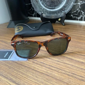 Ray-Ban Wayfarer leopardmönstrade solglasögon - Snygga Ray-Ban Wayfarer solglasögon med leopardmönstrad brun plastbåge och mörka glas driving glas ( grön grå ). Klassisk modell med Ray-Ban-logga på skalmen. Kommer med originalfodral och putsduk. Obetydligt använda, RB inristat i v glas inga repor eller märken fodralet kan ha något minimalt märke, 