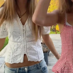 Vit broderad blus från H&M - Superfin vit blus från H&M med broderade detaljer och v-ringning. Blusen har korta puffärmar, knappar framtill och är tillverkad i bomull. Perfekt för en somrig look med jeans eller kjol. Söt och luftig med romantiska vibbar!