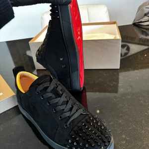 Svarta sneakers med nitar från Christian Louboutin - Säljer ett par svarta sneakers från Christian Louboutin med svarta nitar. Jag säljer skorna eftersom jag fick dom i present men dom tyvärr inte passade. Tillkommer: dustbag, box, kvitto, box och en påse med extra nitar.
