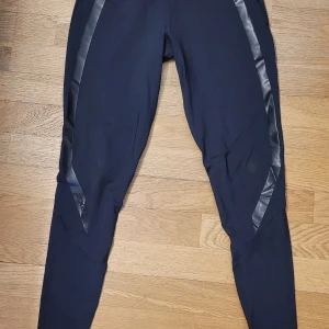 Svarta träningstights från 2XU kompressionstights M - Svarta träningstights från 2XU med diskreta detaljer längs benen. Tightsen är kompressionstights så perfekta även för hård beslastning och ökad cirkulation! Snygg liten logga på ena benet. Storlek M. Använda ett par ggr bara, har bytt till Large.