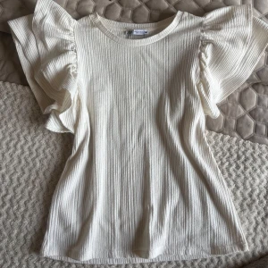 Vit ribbad topp med volangärmar från Zara - Säljer en vit ribbad topp från Zara med stora volangärmar.  