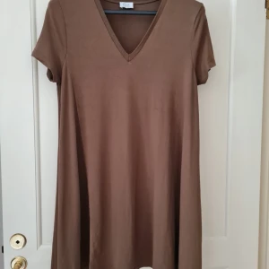 Tunika med v-ringning från Zara strl L (dam) - Säljer en enkel och stilren khaki tunika från Zara med v-ringad hals och korta ärmar. Klänningen har en avslappnad passform och är tillverkad i mjuk bomull. Bilden ser brun ut men i verkligheten är den khaki färg. Storlek L. Kan hämtas i Vallentuna.