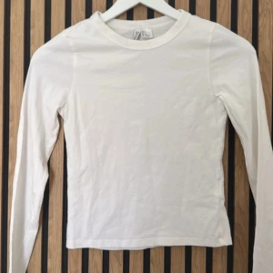 Vit långärmad topp från hm - En enkel och stilren vit långärmad topp från Divided. Modellen är tight och har rund halsringning. Perfekt att styla med jeans eller kjol för en clean look.
