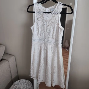 Vit spetsklänning  - Superfin vit klänning med blommig spets. Perfekt för sommarens tillfällen eller studentfirande. Dragkedja i ryggen för enkel på- och avtagning. Använd en gång, vid min egen student. Det sitter jättebekvämt och fint.
