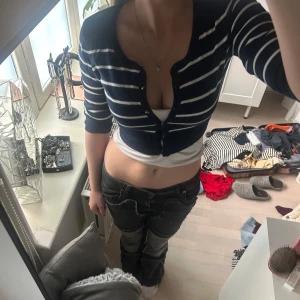 Mörkblå croppad kofta med vita ränder - Säljer en mörkblå croppad kofta med vita horisontella ränder och knappar framtill. Tröjan har trekvarts ärm. Perfekt för dig som gillar en trendig och avslappnad stil.