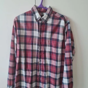 Rutig skjorta från Dressmann strl L - Säljer en klassisk rutig skjorta från Dressmann i rött, blått och vitt. Skjortan har lång ärm, knappar framtill och bröstficka. Tillverkad i 100% bomull. Storlek L. Kan hämtas i Vallentuna.