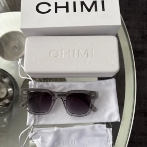 CHIMI 04 – Grey - Säljer ett par stilrena CHIMI 04 solglasögon i grått. Klassisk fyrkantig design i transparent grå båge och mörktonade linser. Solglasögonen är i nyskick och levereras komplett med originalbox, hårt etui och putsduk. Perfekt både till vardag och semester! Nypris: ca 1 200                                                                          Pris kan diskuteras vid snabb affär 
