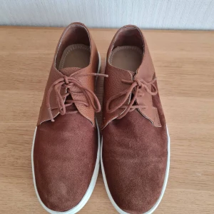 Mocca sneakers med snörning strl 41 - Snygga bruna mocca sneakers från Reserved med ovandel i både mocka och skinn. Skorna har rund tå, vita platta sulor och klassisk snörning framtill. Använda få gånger. Storlek 41. Kan hämtas i Vallentuna.