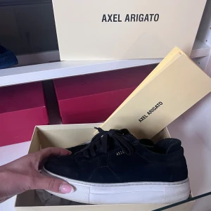  Axel Arigato skor - Säljer ett par svarta sneakers från Axel Arigato med vit, tjock platt sula och snörning. Storlek 37. Finns inte att köpa längre. Väldigt fint skick. Dock sulan lite trasig på ett ställe därav lägre pris. Inget man ser eller känner.
