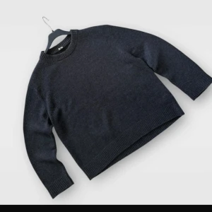 Mörkgrå stickad tröja från Arket - Säljer en enkel och stilren mörkgrå stickad tröja med rund halsringning. Tröjan har långa ärmar och breda ribbade muddar vid ärmslut och nederkant. Perfekt för kyligare dagar och passar till det mesta.