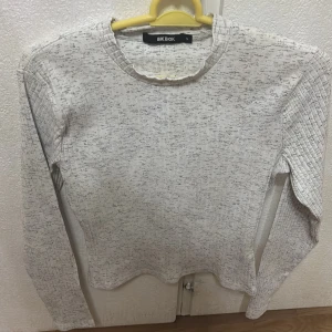 Ljusgrå ribbad långärmad tröja från Bik Bok - Säljer en ljusgrå långärmad tröja från Bik Bok med diskret mönster och ribbade detaljer. Tröjan har rund halsringning och är perfekt för lager-på-lager. Enkel och stilren design som passar till mycket.