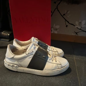 Valentino Open sneakers i vitt och svart - Snygga Valentino Open sneakers i vitt med en bred svart rem över ovansidan. Skorna har en klassisk design med snörning och en bekväm sula. Perfekta för en stilren look. Dom har släppt lite fram i foten men de går lätt att fixa vid en skomakare! Vill hälsat byta dom mot några fräscha skor men de går att köpa om man kommer med ett bra pris hör av er vid minsta lilla funderingen! Själv skulle jag säga att dom är dom snyggaste skorna som har varit vid min ägo.Dom är självklart äkta.