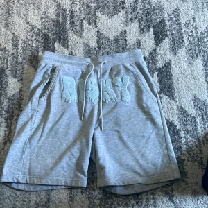 Risky shorts - Snygga grå shorts från Risky med text framtill den är storlek M men passar bra för L också, bara använda en gång i några timmar och tvättad. Pris kan diskuteras