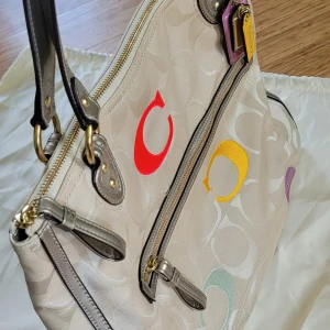 Äkta Coach Väska nästintill nyskick! - Säljer en sandfärgad originalväska från Coach som är köpt i NewYork. Nästintill nyskick! Väskan har dragkedja och ytterfack och två innerfack. Medföljer väskpåse. Mått ca 40×30cm. Fin present till en medveten eller dig själv! 😀