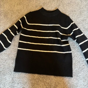 Svart stickad tröja  från Vero Moda - Säljer en svart stickad tröja från Vero Moda med vita ränder. 